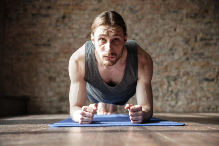 Serious strong sportsman in gym make yoga sport exercises.